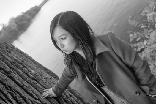 Portrait of young woman leaning against a tree next to a river