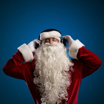 Santa Claus is listening to music on headphones, behind the abstract background