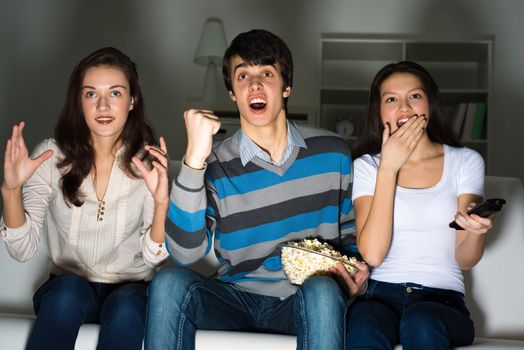 group of young people watching TV on the couch, sports fans