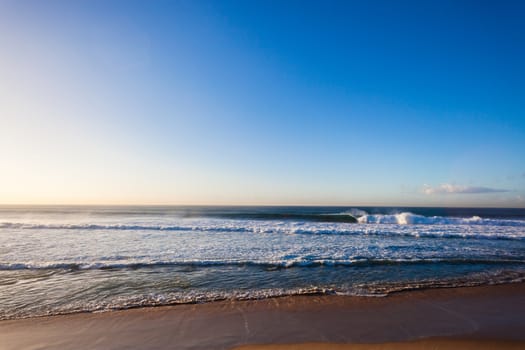 large ocean waves swells crashing breaking towards the beach reefs and sandbars in offshore winds.