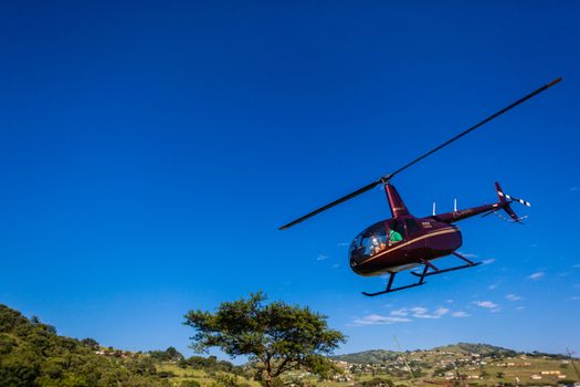 Helicopter pilot passengers taking off into blue morning sky covering a sporting event