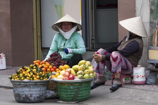 2 street vendors in conversation in Ho CHi Minh City