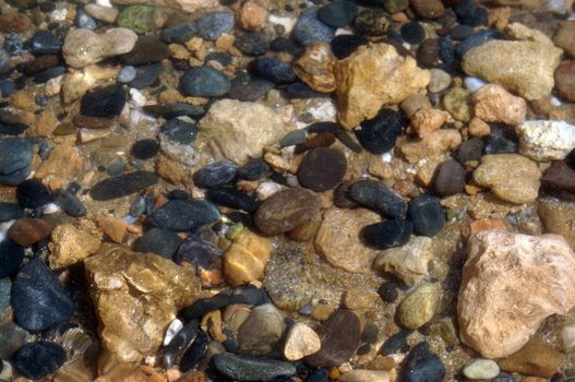 Pebbles on the beach under the water as a background                               