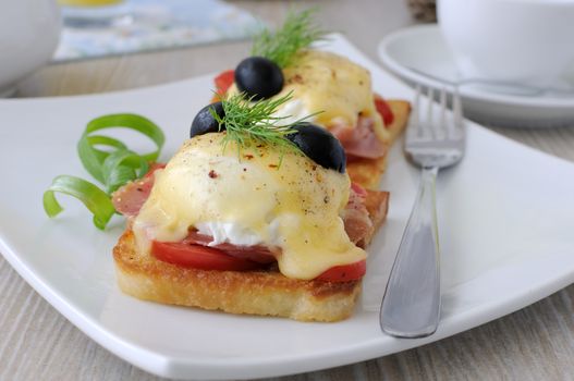 Eggs Benedict with ham and tomato on toast with cheese and olives
