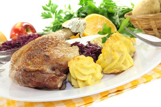 Duck leg with duchess potatoes and red cabbage on a light background