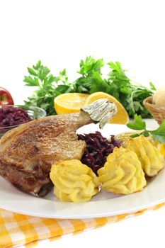 hot Duck leg with duchess potatoes and red cabbage on a light background