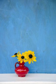 beautiful red vase with yellow flowers on blue background