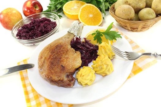 delicious Duck leg with duchess potatoes and red cabbage on a light background