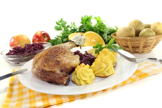fresh Duck leg with duchess potatoes and red cabbage on a light background