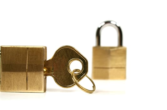 Two small brass padlocks with a key isolated on a white background.