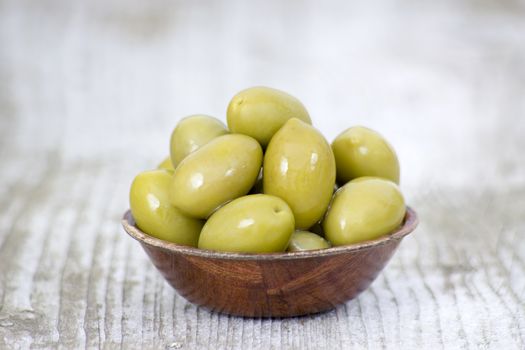 Bowl with freshly whole fresh green olives on a rustic wooden tabletop