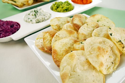 Assorted dips of carrot, cottage cheese and herbs, pea and basil with lavash crisps plus copy space.