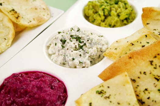 Assorted dips of cottage cheese and herbs, pea and basil with pita crisps.