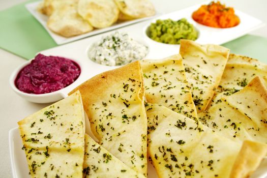 Assorted dips of carrot, cottage cheese and herbs, pea and basil with pita crisps.