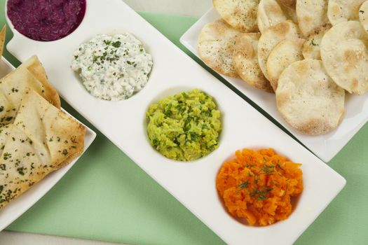 Assorted dips of carrot, cottage cheese and herbs, pea and basil with pita crisps.