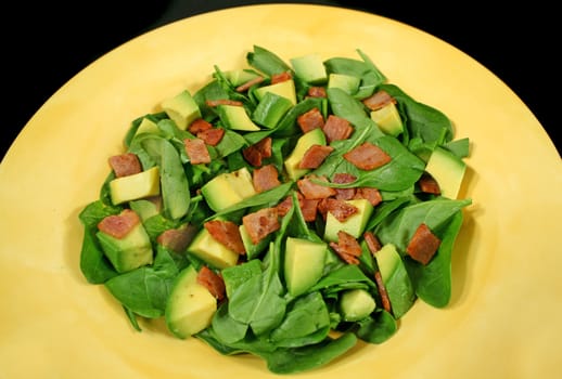 Delightful baby spinach, avocado and bacon salad ready to serve.