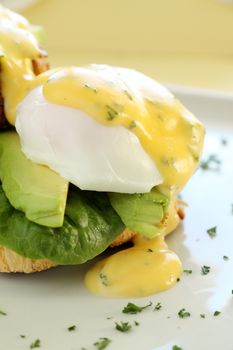 Beautiful eggs benedict with bacon and a rich hollandaise sauce on crusty bread.