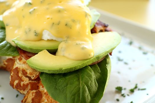 Delicious eggs benedict with hollandaise sauce with avocado.