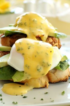 Beautiful eggs benedict with bacon and a rich hollandaise sauce on tiger crust bread.