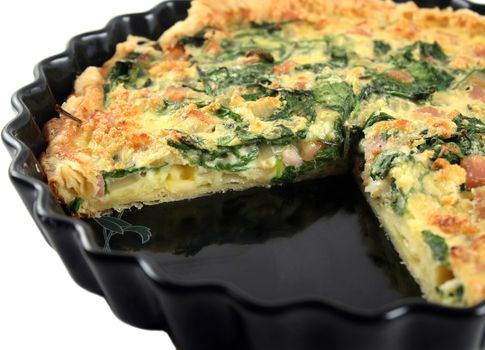 Fresh sliced homestyle spinach and bacon quiche straight from the oven.