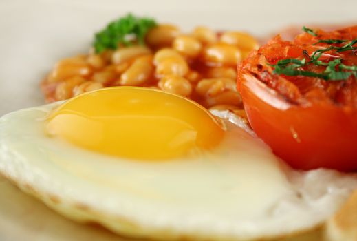 Breakfast of grilled bacon, tomato, egg and baked beans.