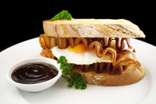 Curled bacon and egg sandwich with BBQ sauce ready to serve.