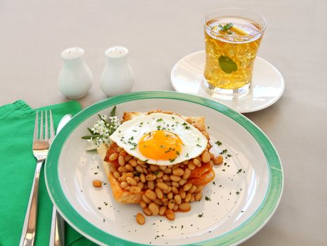 Delicious old fashioned breakfast of a fried egg on a baked beans stack on toast.