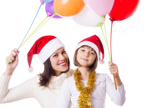 Smiling mother with daughter with balloons and Christmas hats over white