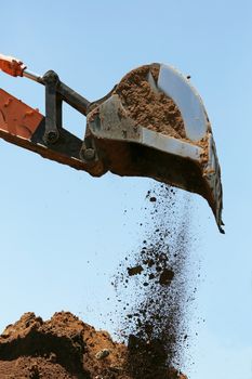 Industrial excavator machine scooping up sand and rocks