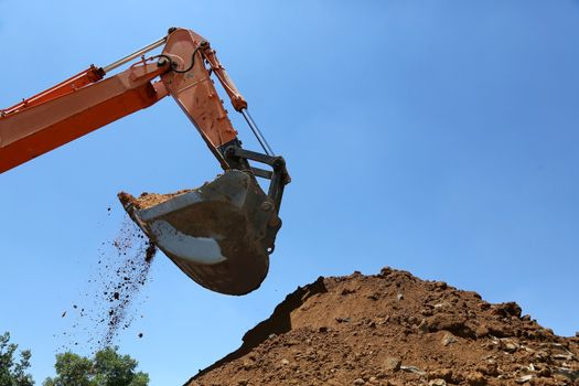 Industrial excavator machine scooping up sand and rocks