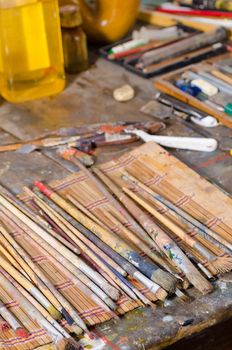 Many paintbrushes on a messy atelier table