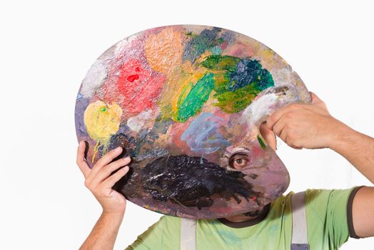 Portrait of an eccentric painter holding his palette in front of his face