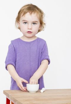 young girl standing behind desk . Studio shot with grey background