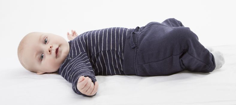 smiling toddler in blue clothing laying down. vertical image