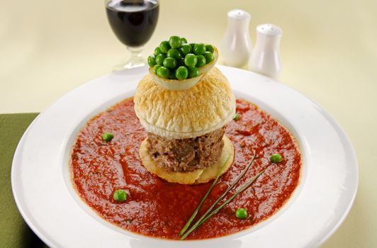 Delicious tall beef pie with peas floating in tomato sauce.