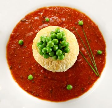 Green peas on top of a pastry base in a tomato sauce with chives.