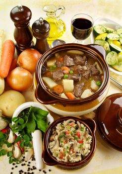 Table setting of freshly baked beef stew with savory rice and seasonal vegetables and herbs.