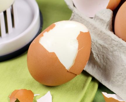 Cracked brown egg with egg carton and slicer.