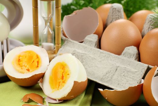 Freshly boiled eggs in half along with a carton of brown eggs.