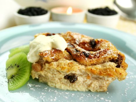 Delicious bread and butter pudding dessert with kiwi fruit and cream.