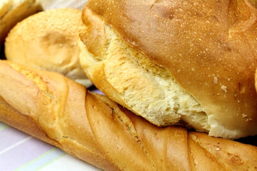 Background of different bread textures with loaves and bread rolls.