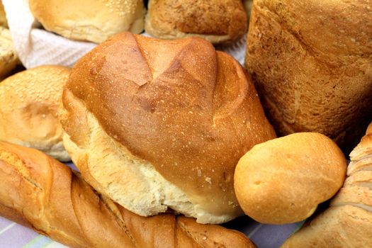 Background of different bread textures with loaves and bread rolls.