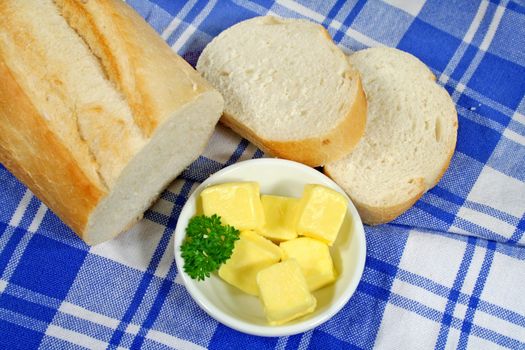 Fresh bread roll and cubes of butter at a picnic.