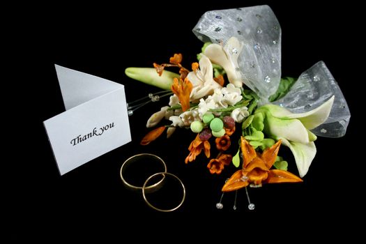 Wedding thank you with rings and decorative bouquet.