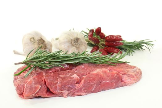 a piece of raw sirloin steak with rosemary and garlic