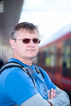 Mature men in glasses with backpack  on train station