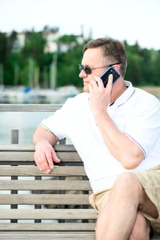 Mature man with the phone on wooden bench