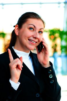 Young happy brunette talking on the phone and shows thumb up.