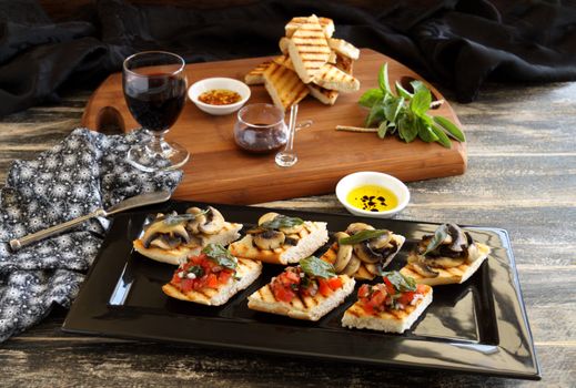 A selection of finger food with mushrooms, tomato and onion including brushette and dips.