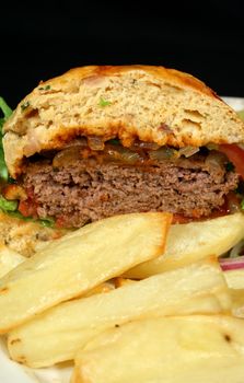 Beef burger cut in half on a herb roll with chips.